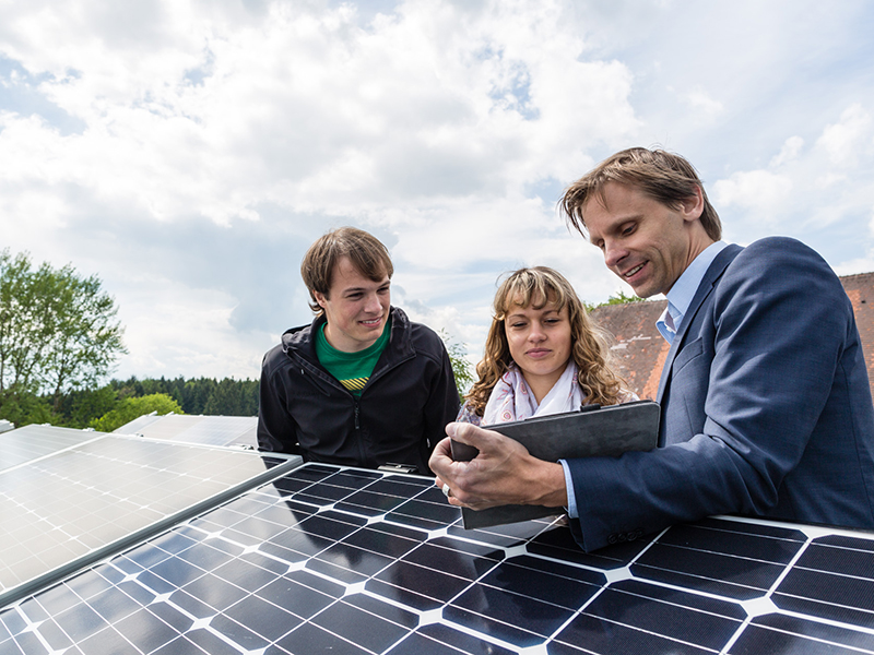 Professor zeigt Studierenden Solarzellen