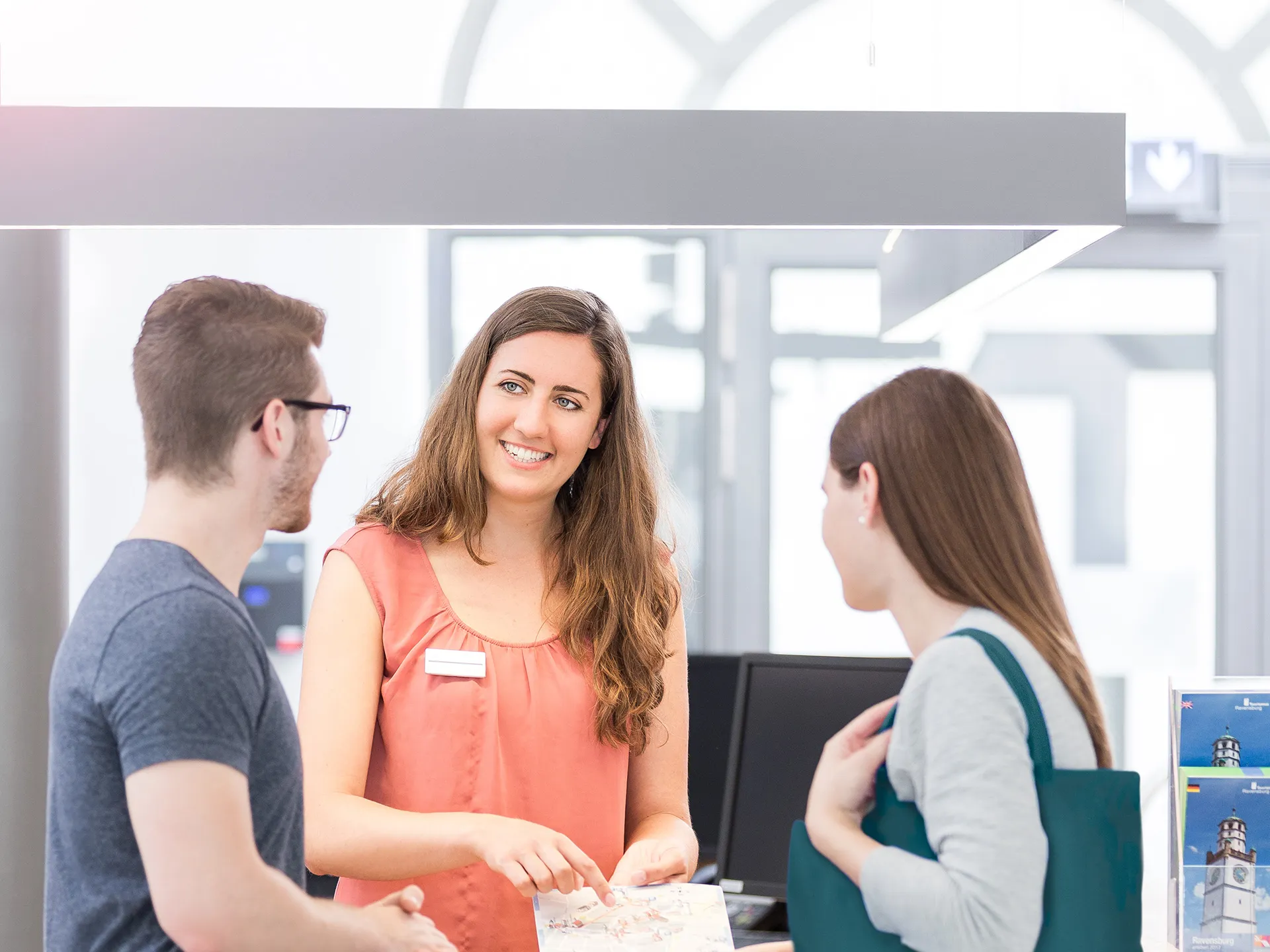 Tourismus-Studentin erklärt Touristen an der Information den Weg