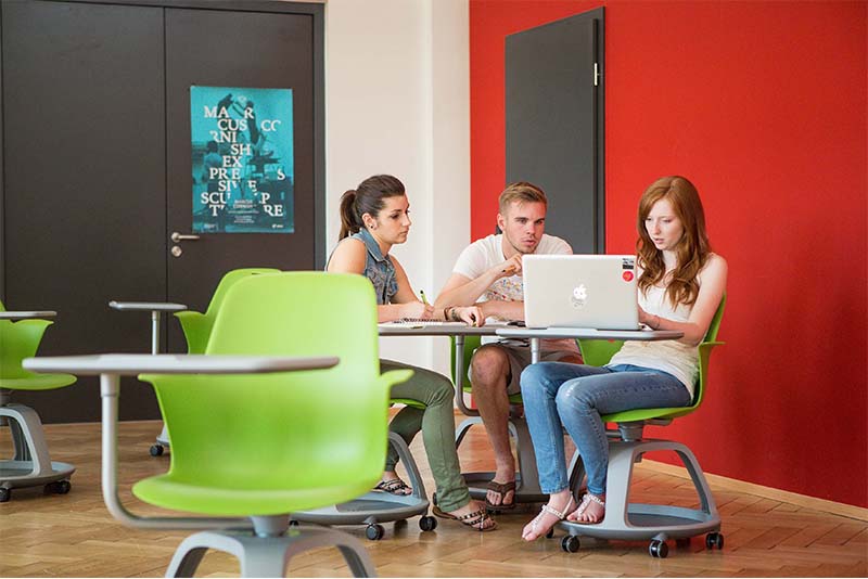 Drei Studierende sitzen an einem Macbook