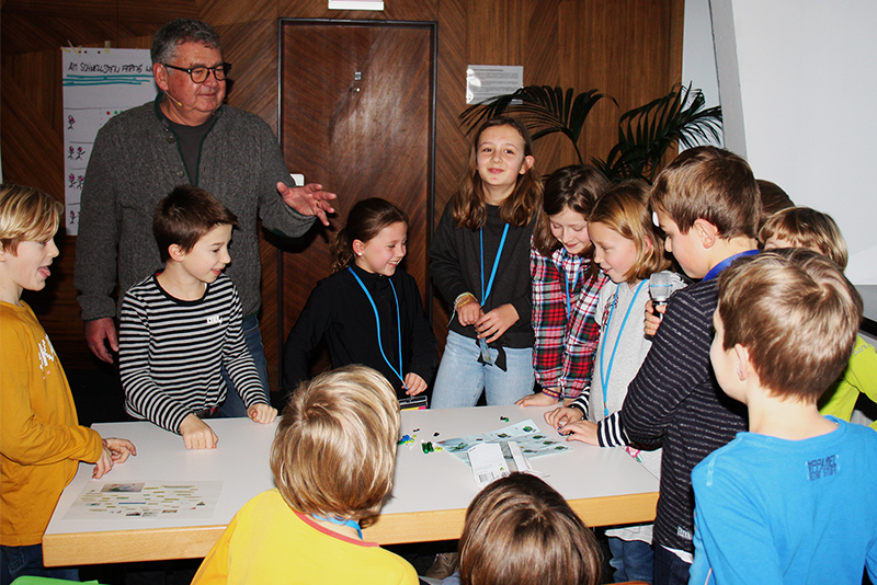 Kinder stehen um einen Tisch, dahinter Prof. Luppold