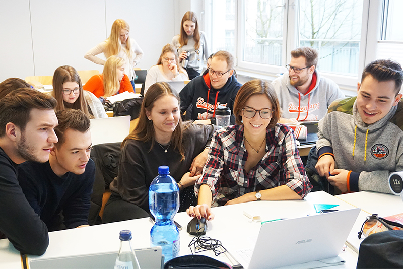 Studierende sitzen vor einem Laptop in einem Vorlesungsraum