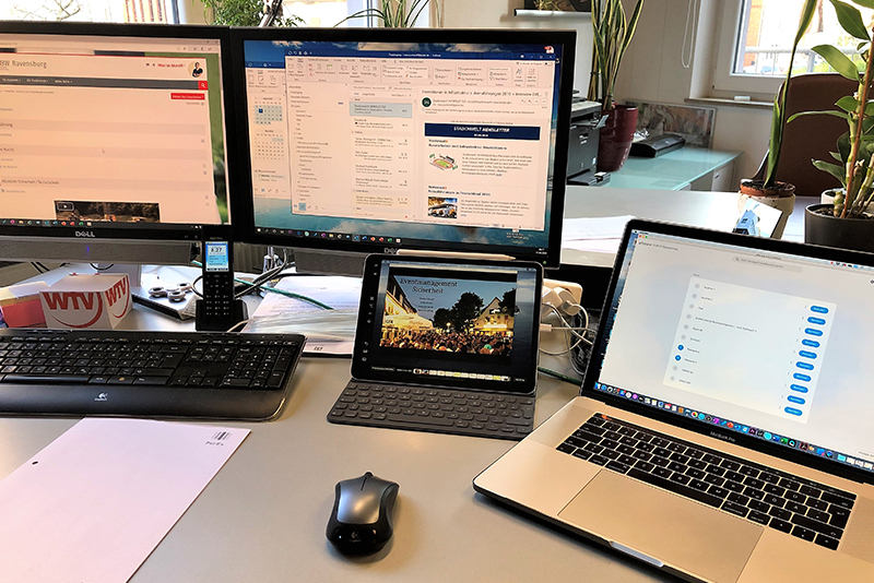 Arbeitsplatz mit zwei PC Bildschirmen, einer Maus, einer Tastatur, einem Laptop und einem Tablet