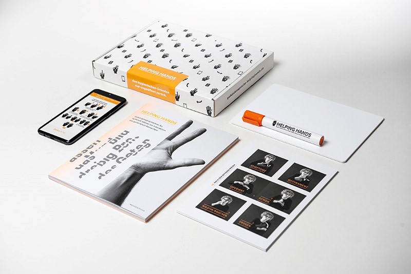 Smartphone, Katalog, Heft und Box im Helping Hands-Design