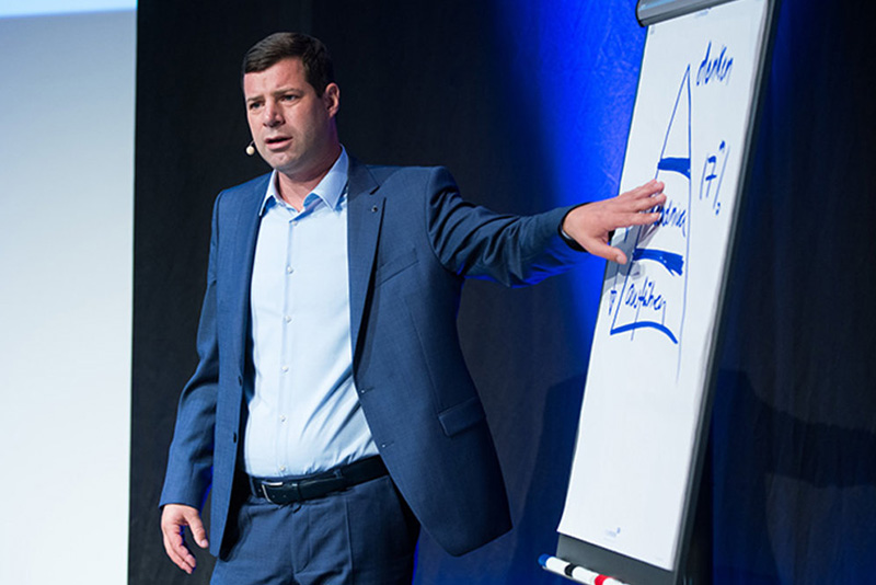 Prof. Dr. Benedikt Hackl erklärt etwas anhand eines Flipcharts