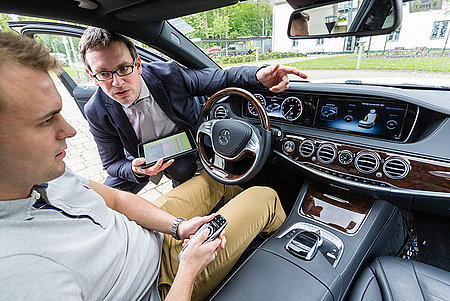 Student und Professor begutachten den Bordcomputer eines Mercedes