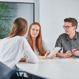 Drei Studierende in einer Besprechung zu Handelsmanagement