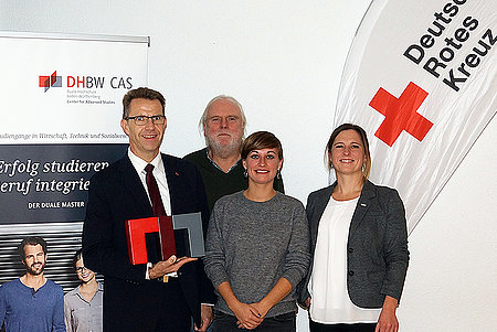 Gruppenbild Frech, Florenz, Lechner und Greiner vor einer Beach Flag des DRK und einem Werbe-Roll-up für den Dualen Master