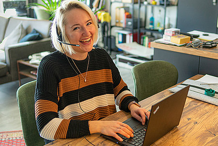 Isabel Mögle lachend mit Headset am Laptop