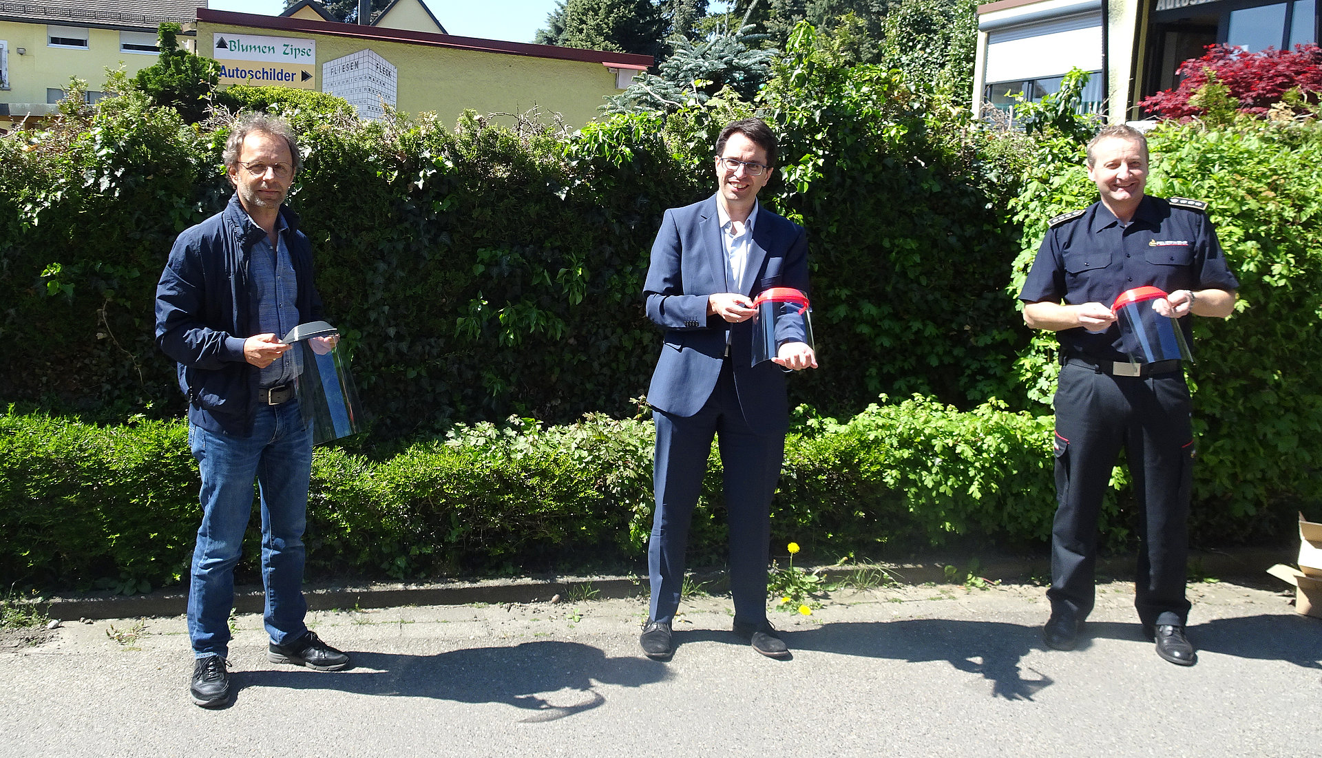 Gruppenbild Rosenstock, Grieb und Schörkhuber vor einer Hecke mit Schutzvisieren in der Hand