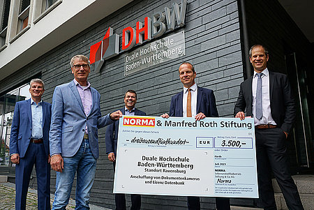 Professoren der DHBW Ravensburg nehmen einen Scheck entgegen